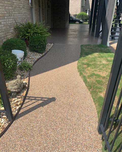 An outdoor patio and walkway made of textured concrete with a speckled pattern in shades of gray and white